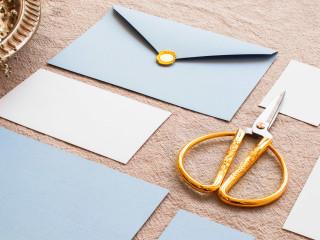 modré a bílé obálky na hnědém podkladu s nůžkami