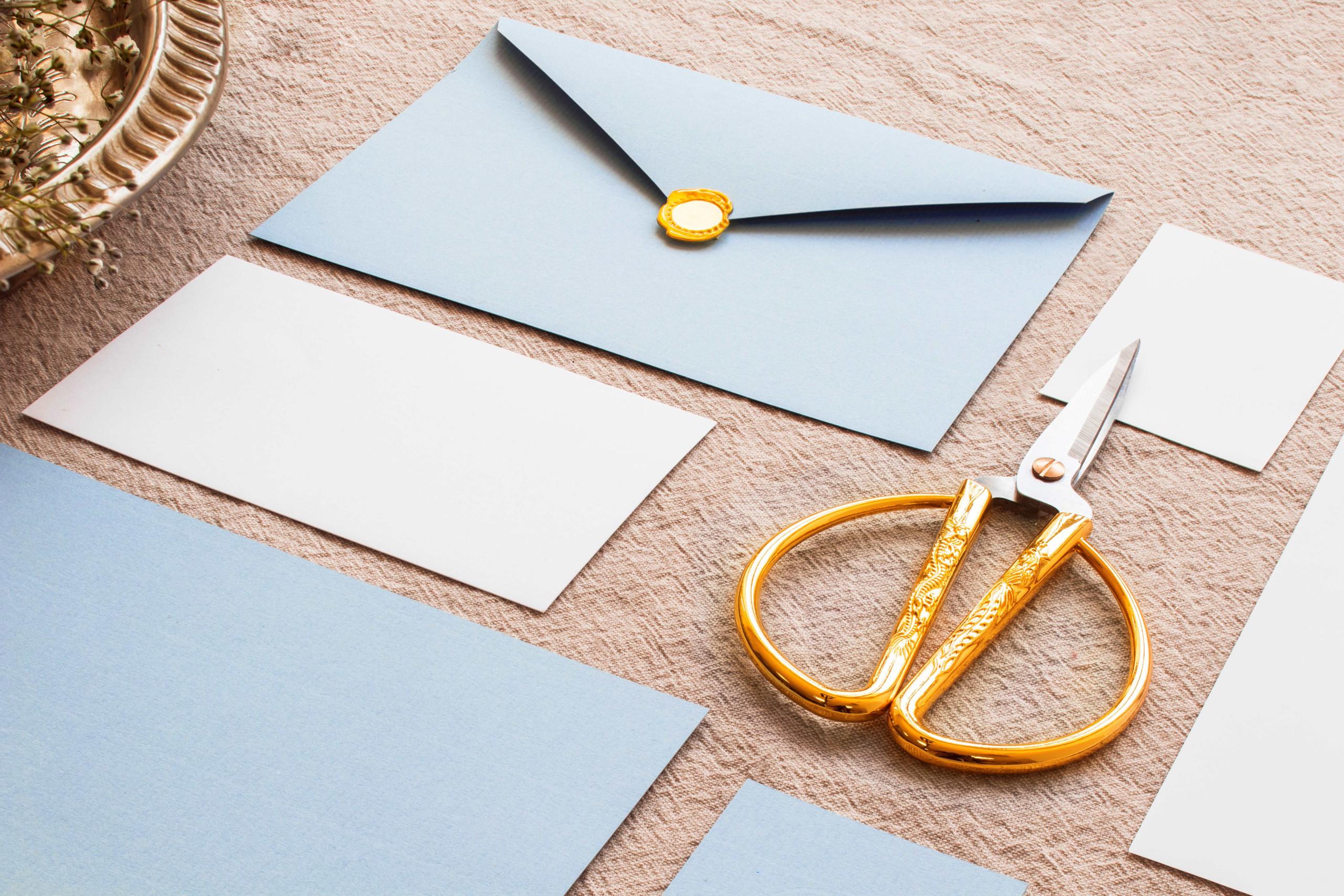 modré a bílé obálky na hnědém podkladu s nůžkami